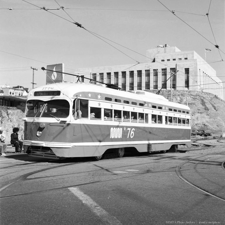 Bicentennial Streetcar 1776 with star-spangled livery on tracks near civic building, 1976