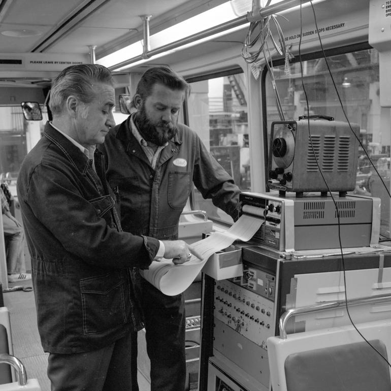 Two technicians examine a computer printout inside a Boeing Light Rail vehicle during testing in 1978.
