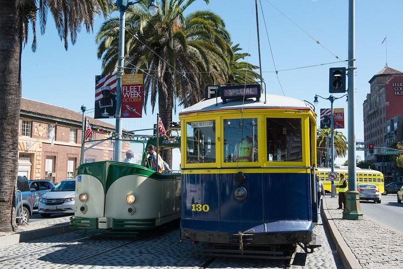 Historic cable car number 130 with yellow and blue livery on San Francisco street near Ferry Building.