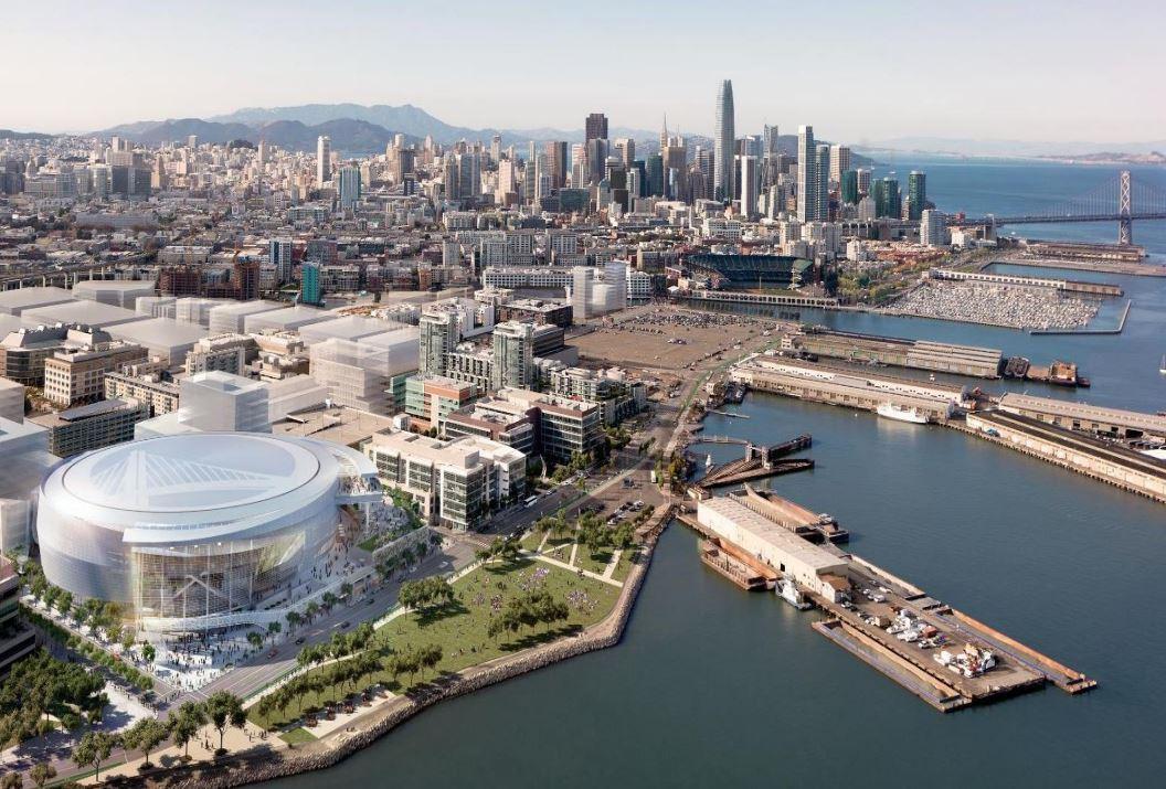 Aerial view of Mission Bay waterfront with proposed arena, San Francisco skyline and Bay Bridge visible.