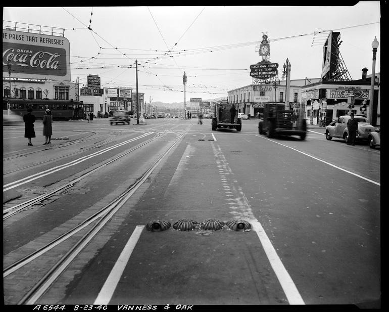 Van Ness Avenue looking south toward Market Street, 1940. Streetcar tracks, vintage vehicles, and commercial buildings visible.