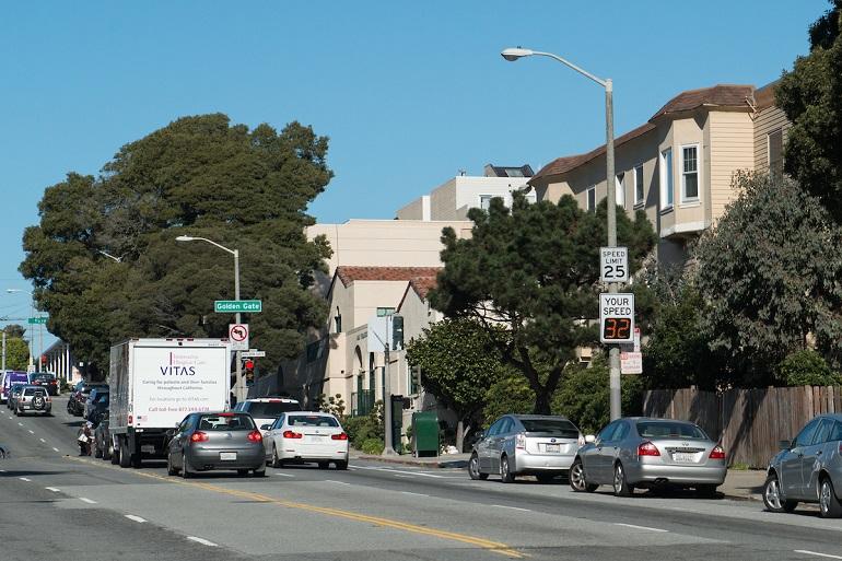 Cars and truck traveling northbound on Masonic Avenue with speed limit signage visible.