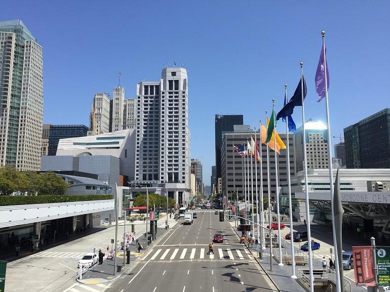 Howard Street at 3rd Street with Moscone Center, downtown San Francisco high-rises, and international flags.