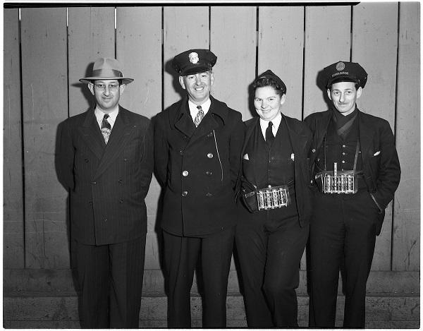 Four Muni employees in 1947 uniforms: inspector in fedora and suit, operator in police-style cap, conductor with medals, and another uniformed staff member.