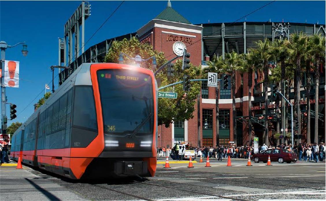 Red and black light rail train on street in front of brick building with clock tower and palm trees.