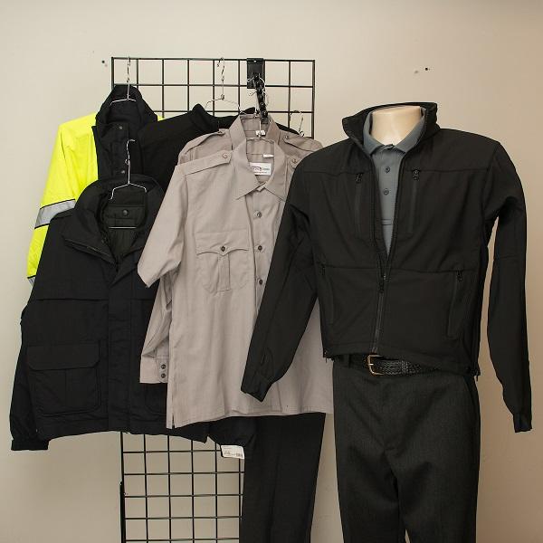 Muni transit worker uniforms displayed on mannequins and hangers, including black and beige jackets with reflective stripes and a yellow safety vest.