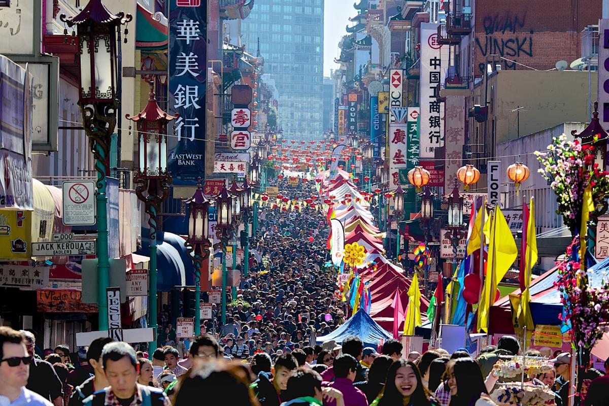 Massive crowd fills Grant Avenue in San Francisco's Chinatown during Lunar New Year celebration with colorful decorations and lanterns.
