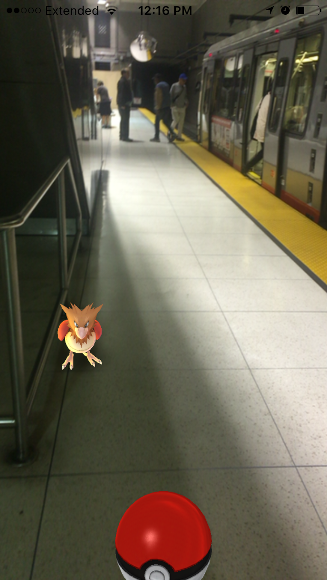 Pokémon Go character on floor of Muni subway station platform with train at dock.