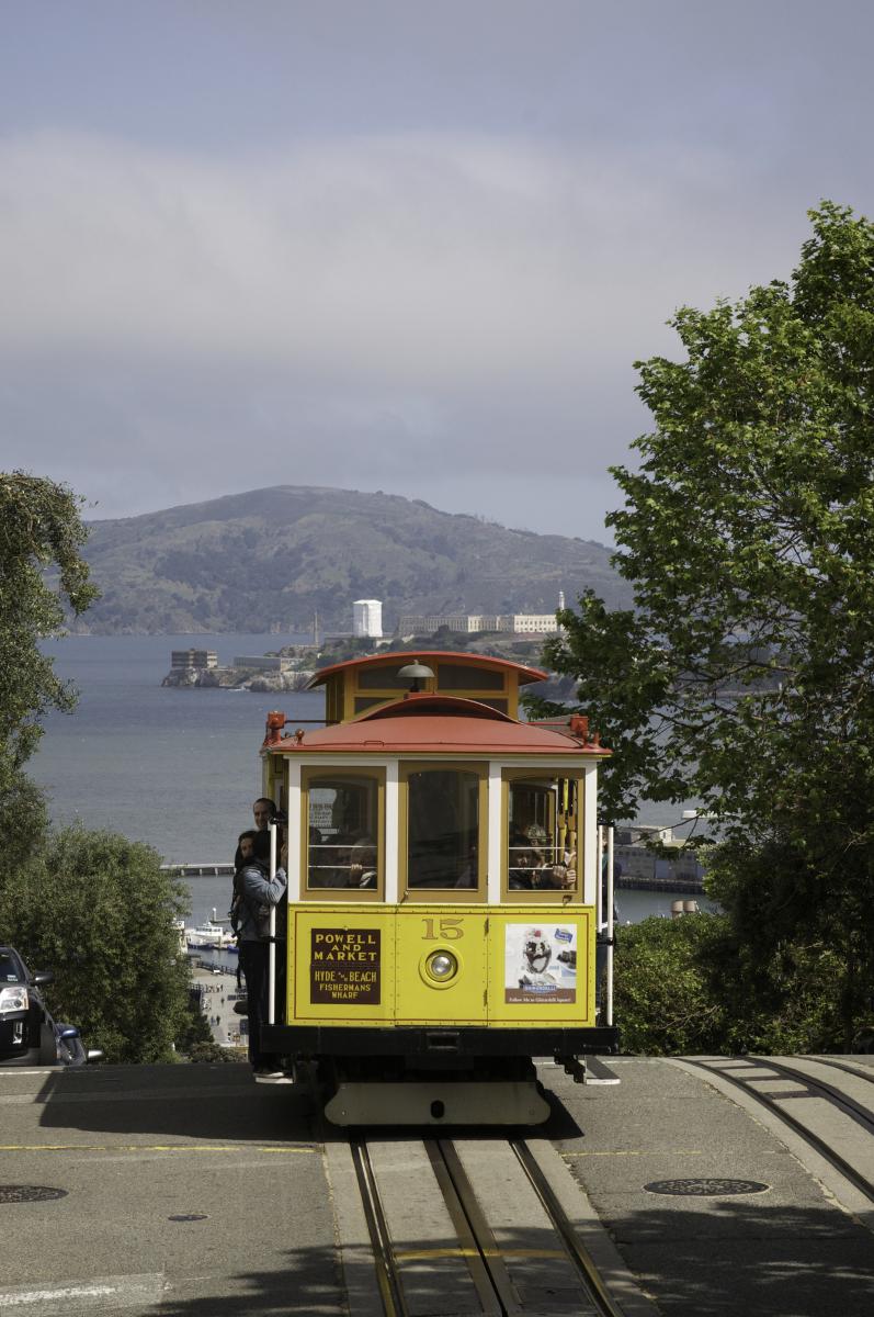 Powell Hyde cable car number 15 on Hyde Street with San Francisco Bay and Alcatraz Island in background.