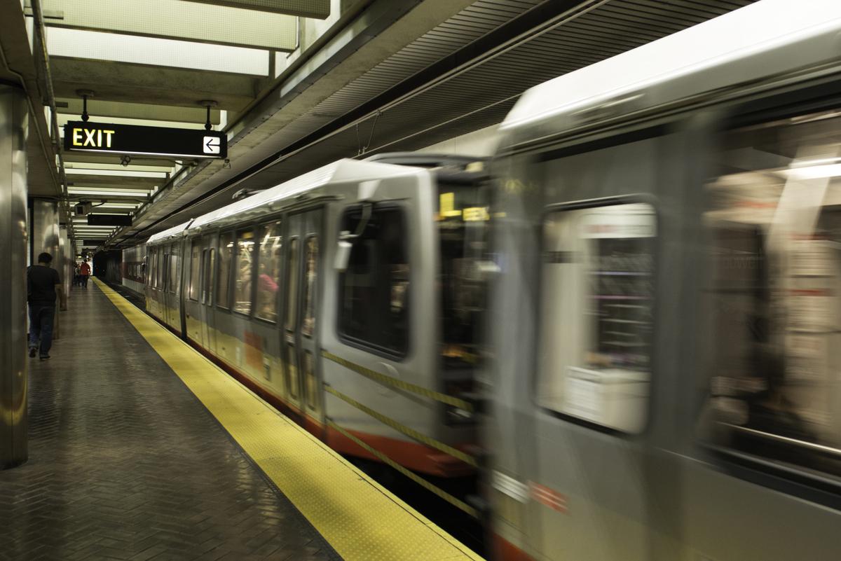 A subway train arrives at Powell Street Station platform with yellow safety strip visible along the edge.