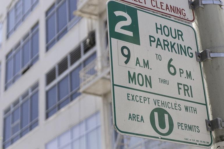 Green and white street parking sign showing 2-hour parking limit 9 A.M. to 6 P.M. Monday through Friday, except for Area U permit holders.