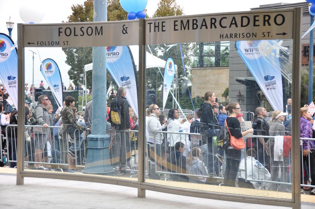 Street sign at Folsom and The Embarcadero with crowds gathered behind barriers for SF Marathon event.