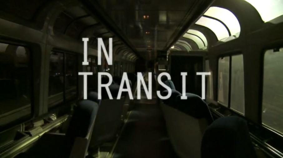 Dark interior of moving Amtrak train car with skylights and "In Transit" text overlay