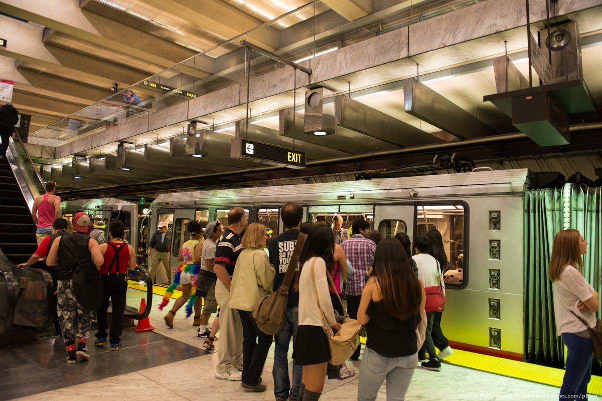 Passengers board and exit a Muni train at Embarcadero Station platform.