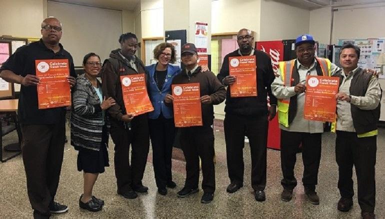 Group of transit workers and staff holding orange Transit Week posters at Presidio Division.