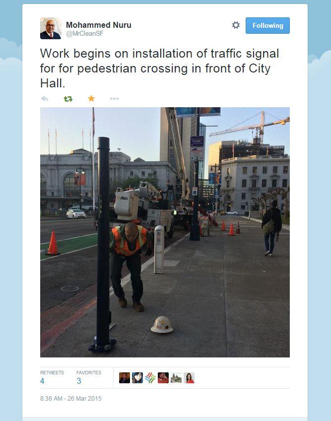Worker in safety vest installs pedestrian traffic signal on Polk Street in front of City Hall using cherry-picker lift.