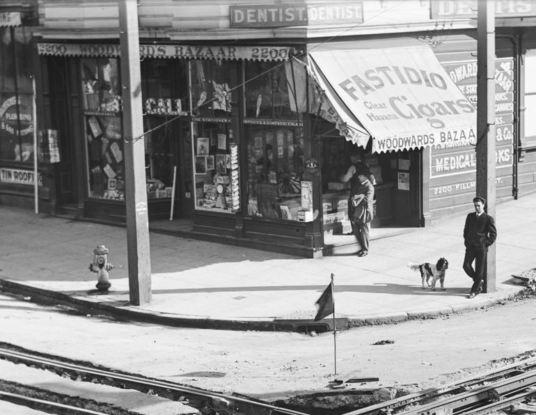 Black and white photograph of Woodward's Bazaar corner store at Fillmore and Sacramento Streets, 1905, with pedestrians and streetcar tracks visible.