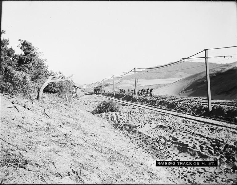 Workers raise streetcar tracks on sandy Lincoln Way amid tall dunes, January 1906.