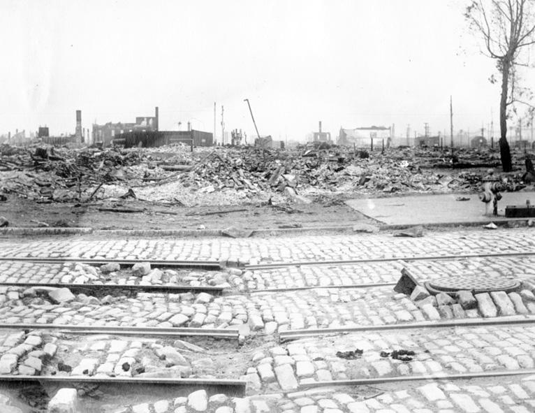 Damaged streetcar tracks and cobblestones at 10th and Brannan streets, San Francisco, May 1906, with destroyed cityscape beyond.