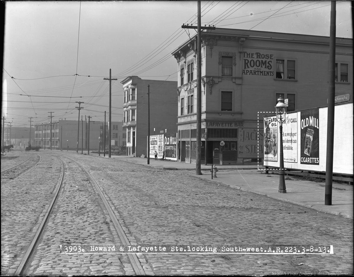 Howard and Lafayette Streets looking southwest, 1913. Streetcar tracks, Rose Rooms Apartments, Lafayette Bar, and vintage advertisements visible.