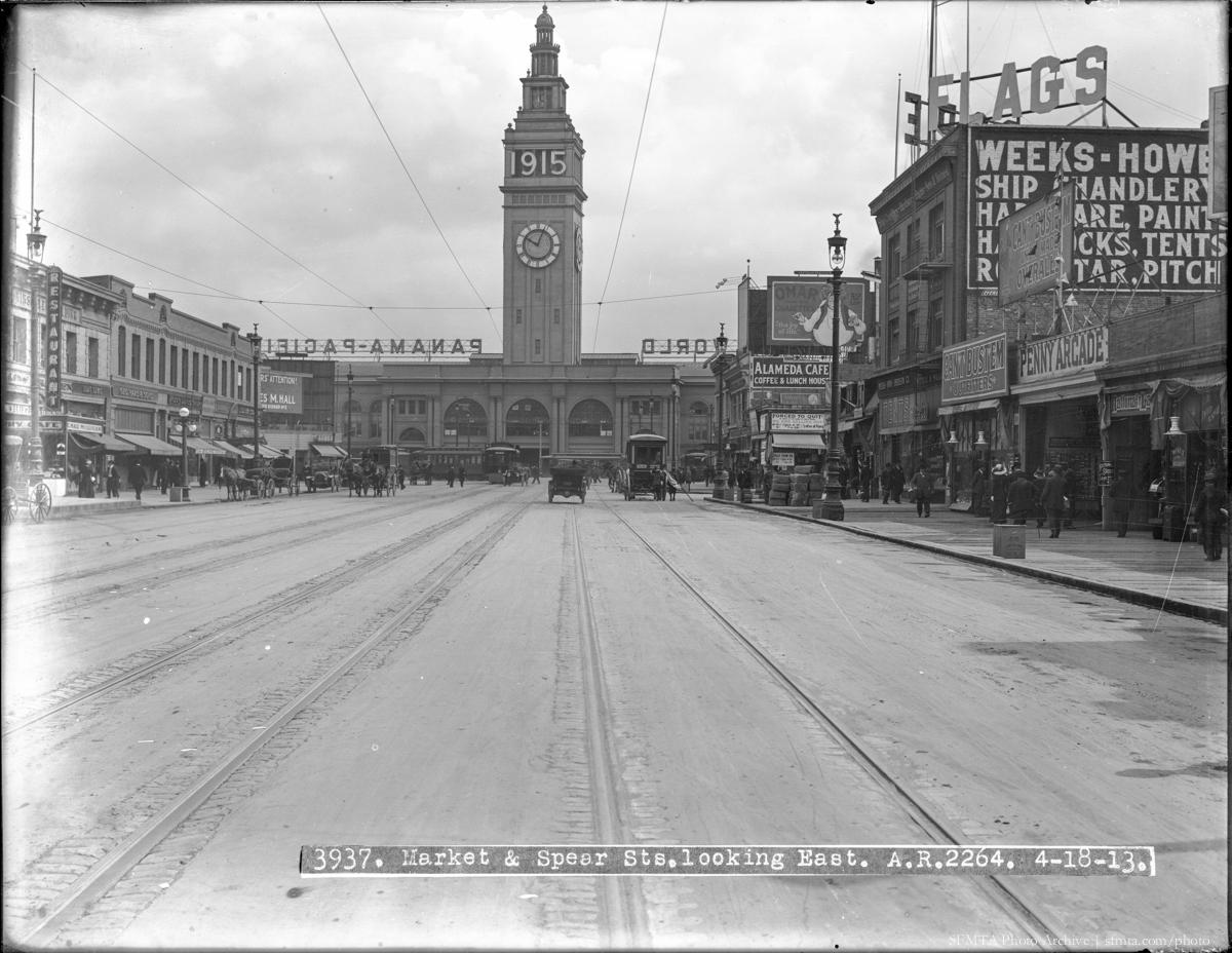 Market and Spear Streets looking east toward Ferry Building, 1913. Streetcar tracks, early automobiles, historic storefronts, and clock tower visible.