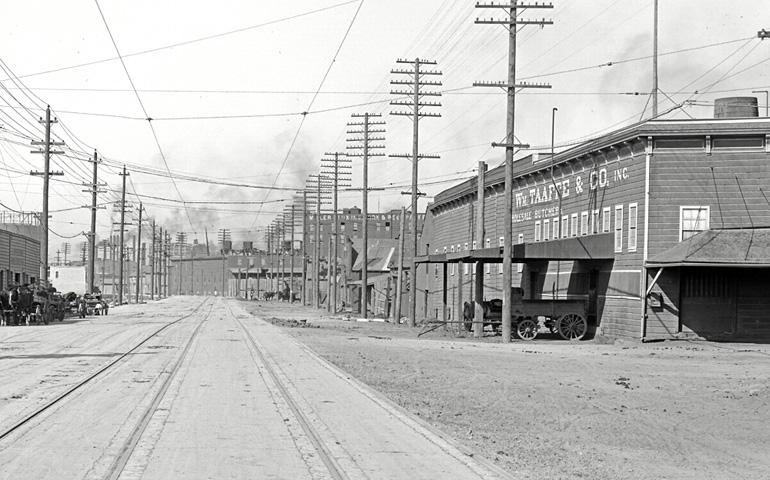 Historic street view showing railroad tracks, utility poles, and Taaffe Company building in early 1900s industrial area.