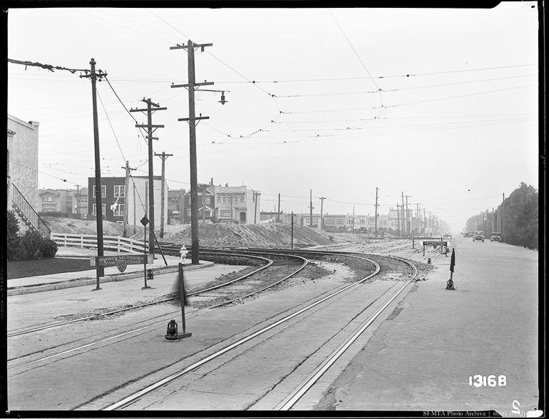 Streetcar tracks under construction at Lincoln Way and 36th Avenue, with utility poles and sand dunes visible, December 1931.