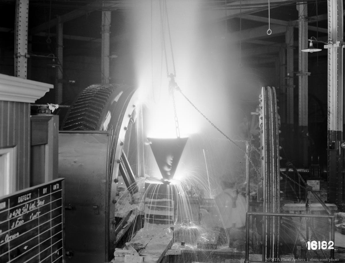 Worker welding a broken shaft at Washington Mason Powerhouse, 1936.