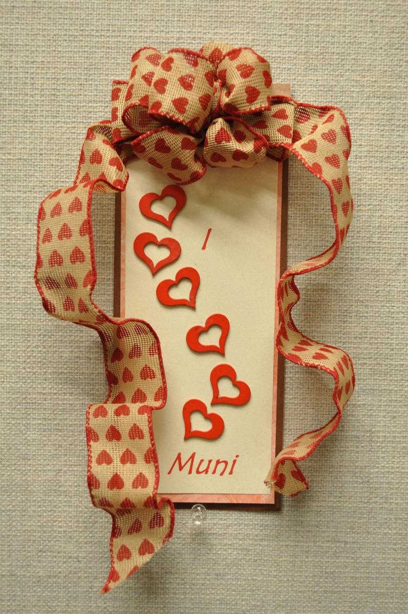 Handmade valentine card with red hearts and "Muni" text, decorated with heart-patterned burlap ribbon bow.