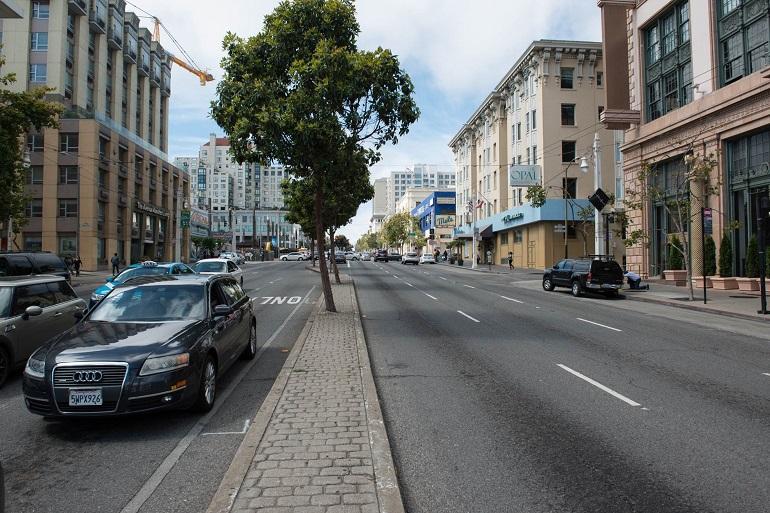 Van Ness Avenue street view with parked taxi, buildings, and tree-lined sidewalk.