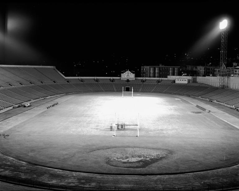Kezar Stadium field at night with floodlights illuminated and empty bleachers, 1949.