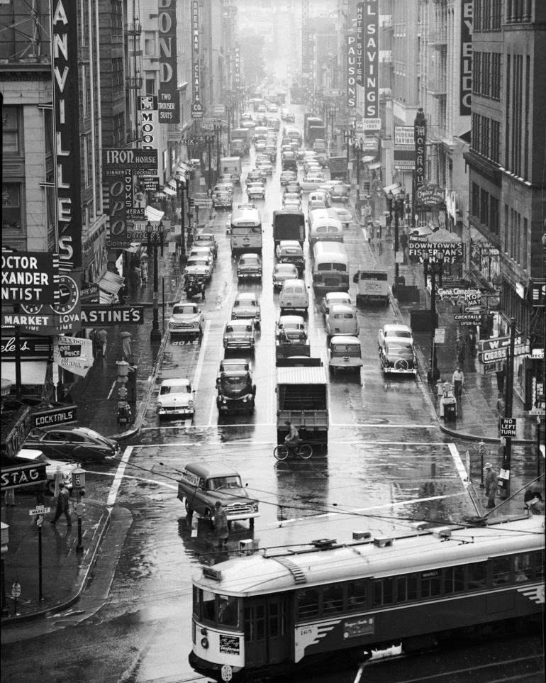 Wet street view looking north on Kearny Street from Market Street, 1957, showing heavy traffic and vintage vehicles.
