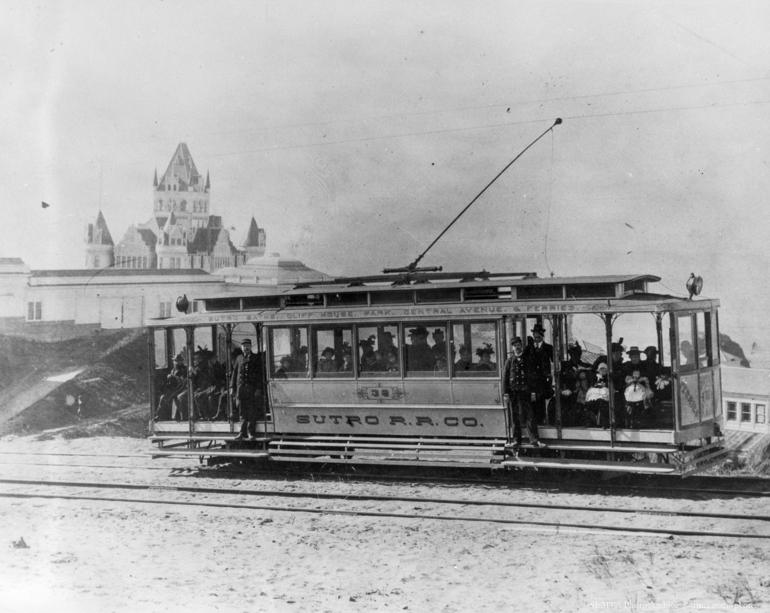 Sutro Railroad Co. streetcar filled with passengers, Cliff House visible in background, circa 1898.