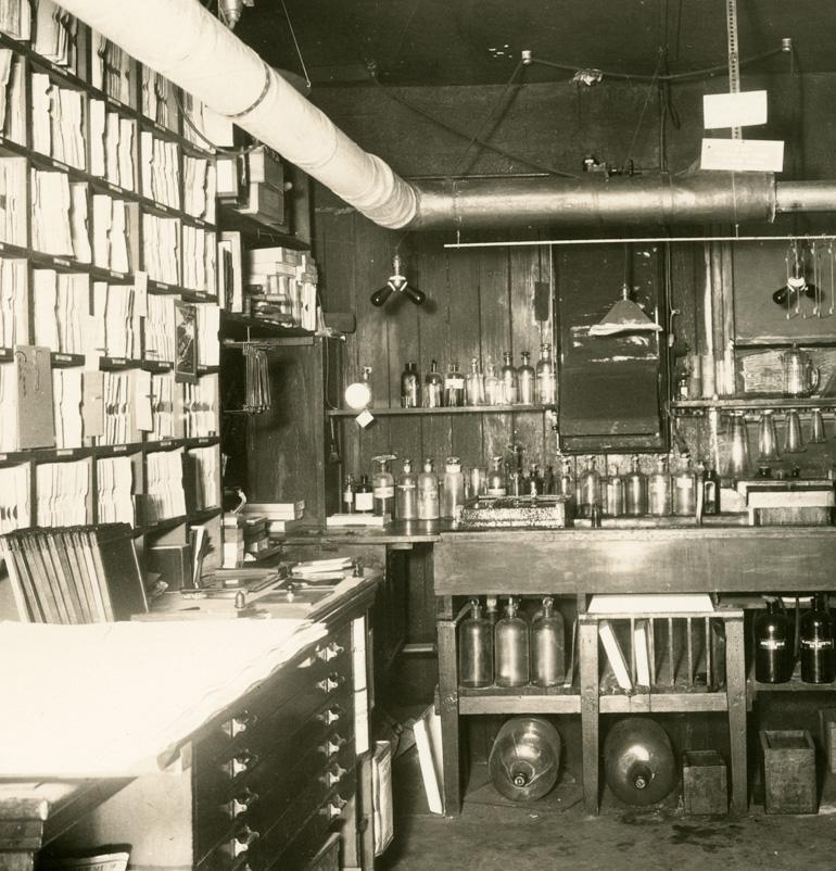 Vintage photography lab with filing shelves, chemical bottles, and darkroom equipment from 1920s United Railroads