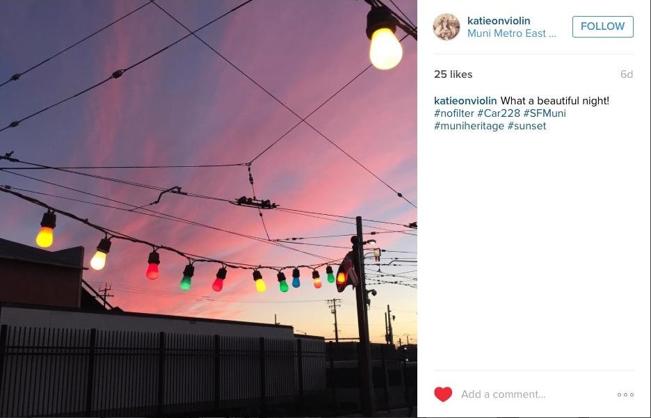 Colorful string lights strung across power lines at sunset with pink and purple sky