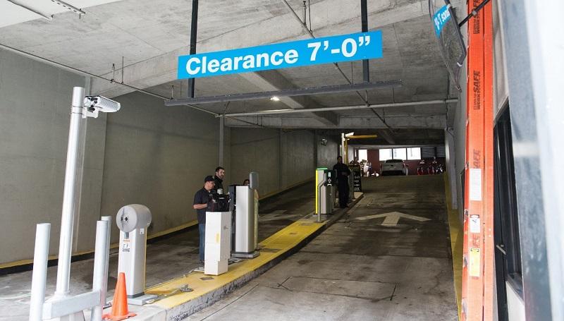 Parking garage entrance with 7-foot clearance sign, white bollards, and license plate recognition system visible.
