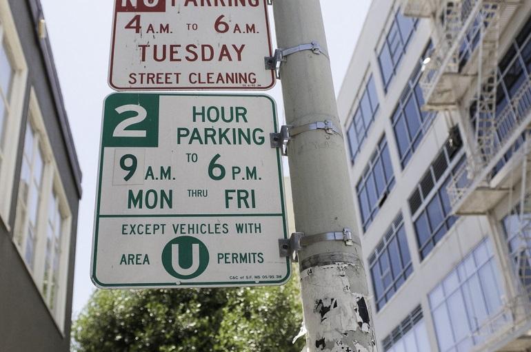 Street sign showing no parking 4-6 AM Tuesday for street cleaning, and 2-hour parking 9 AM-6 PM Monday-Friday except for Area U permit holders.