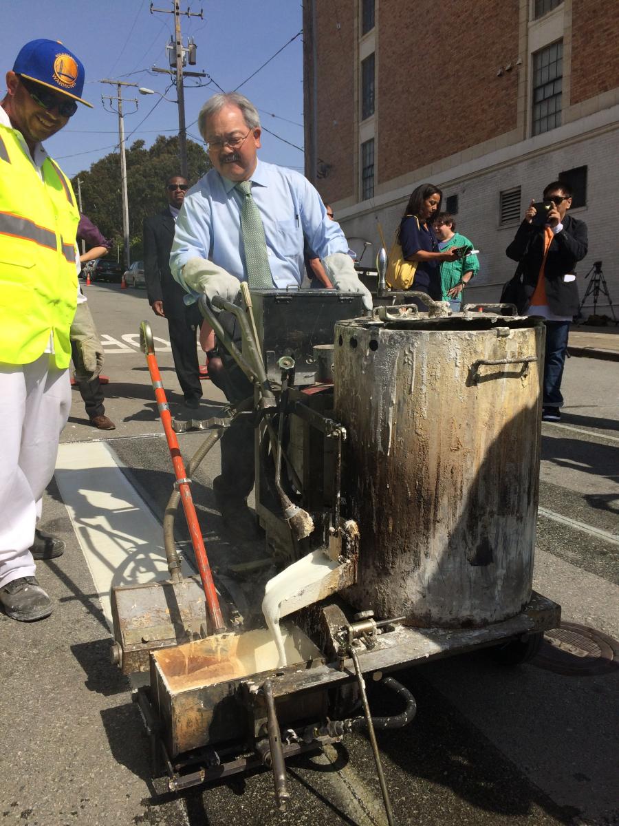 Mayor Lee and paint crew member apply first stripe of paint for crosswalk at Emerson and Geary.
