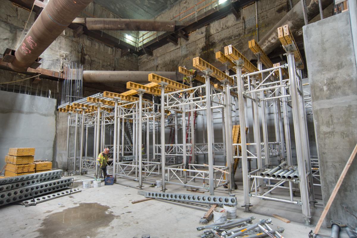Construction scaffolding and concrete forms being built inside a transit station box during platform construction.