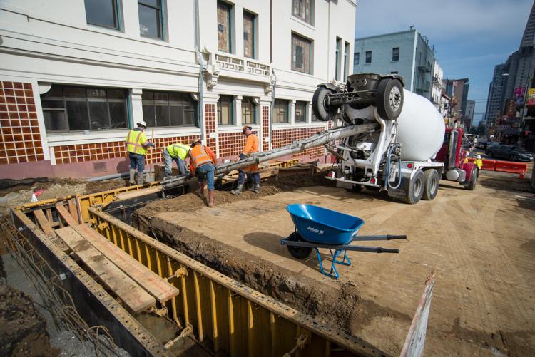 Construction workers pour concrete at Washington and Stockton streets for Chinatown Station project.