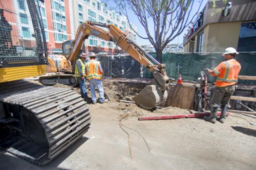 Construction crew operates excavator at 4th and Townsend Street for water line and tunnel work.