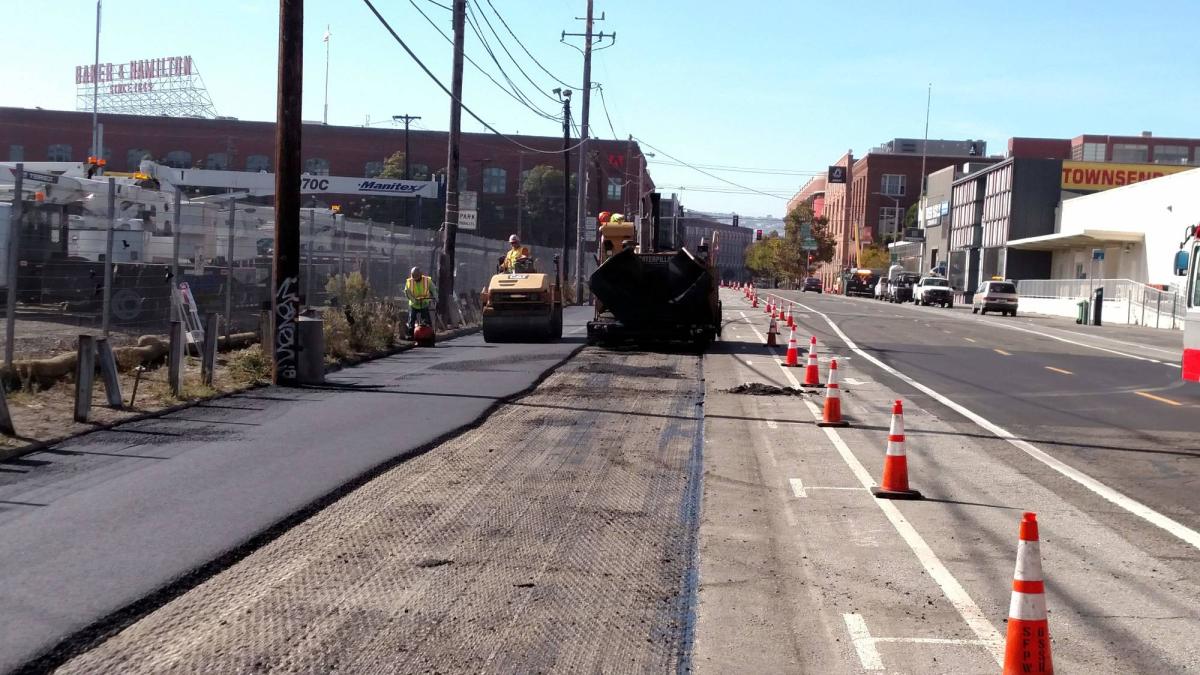 Townsend Street repaving construction with steamroller compacting asphalt and traffic cones lining the work zone.