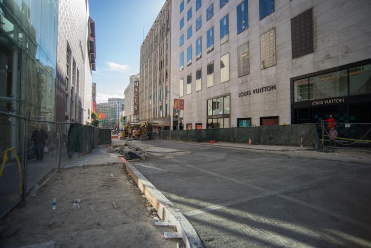 Construction site on Stockton Street with fencing, equipment, and closed lanes in front of Louis Vuitton store.
