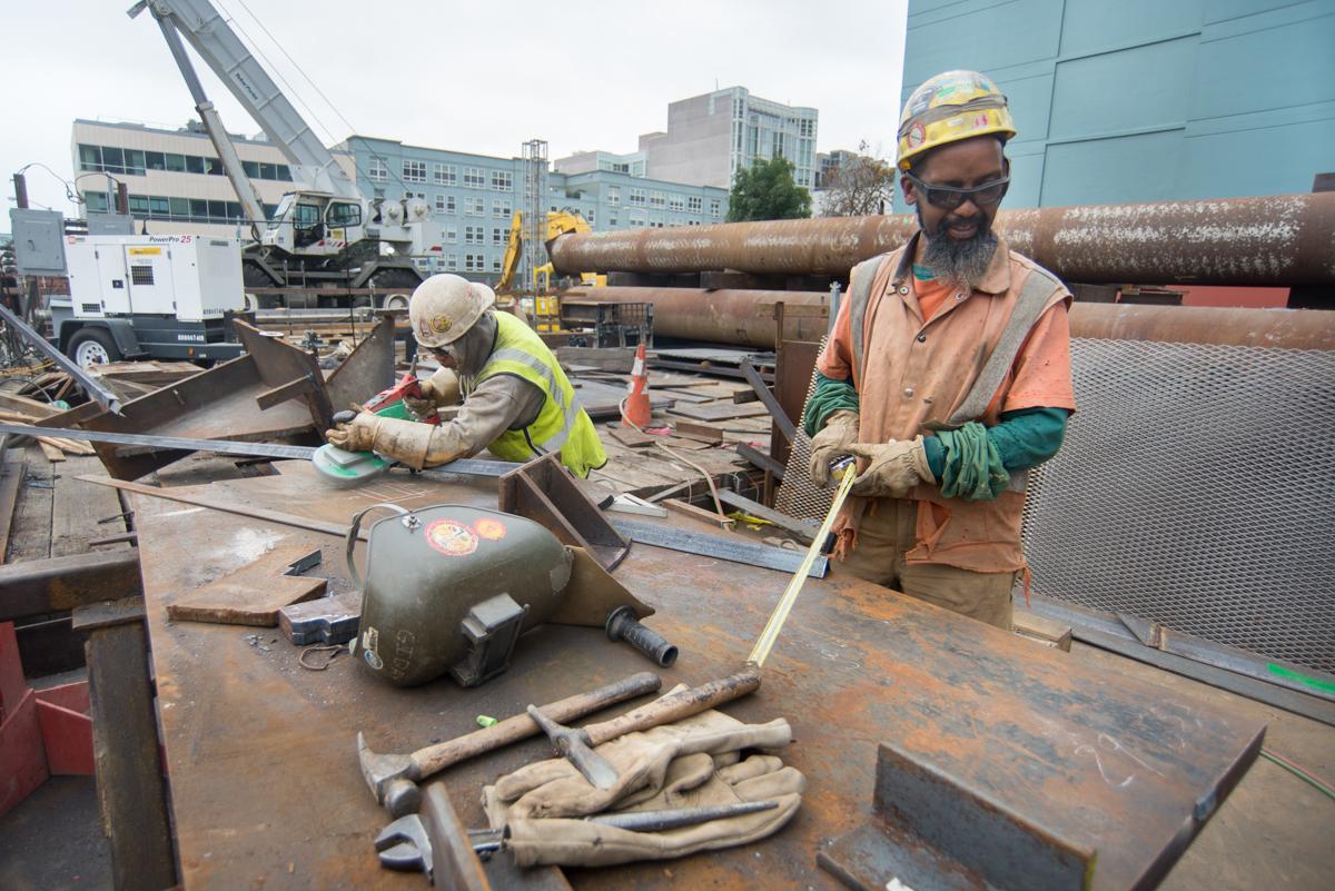 Workers cut and prepare steel bracing materials at Yerba Buena Moscone Station construction site.