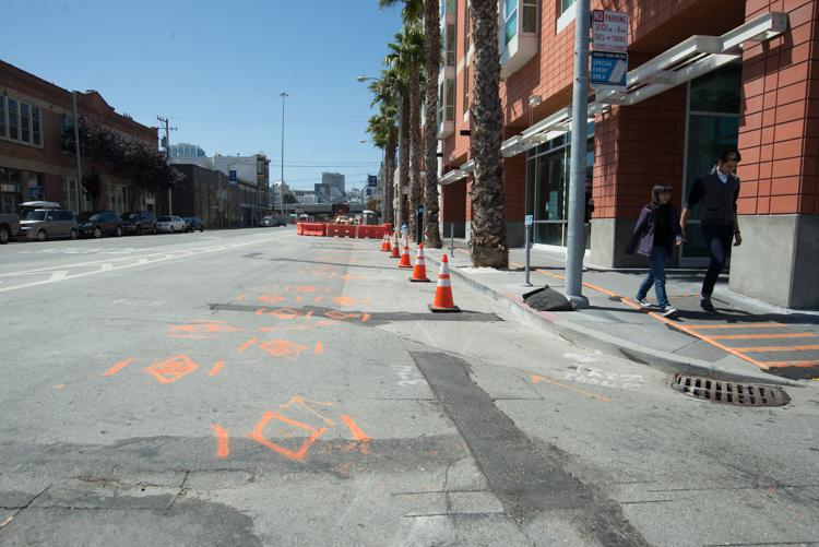 Street construction site with orange utility markings, traffic cones, and palm trees on 4th Street in San Francisco.