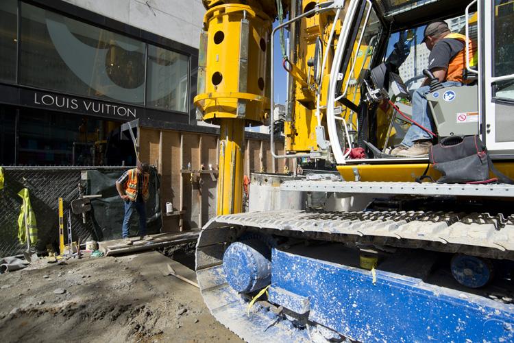Construction equipment and workers on Stockton Street near Louis Vuitton storefront during Union Square Station project.
