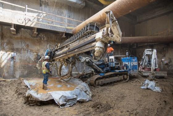 Drill rig injecting concrete-waterproofing grout solution underground at Chinatown Station construction site.