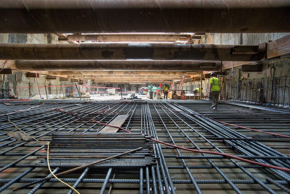 Rebar grid installation for transit headhouse construction under elevated highway structure.
