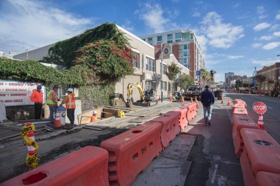 Construction workers excavate street at 4th and Bryant streets for utility relocation work.