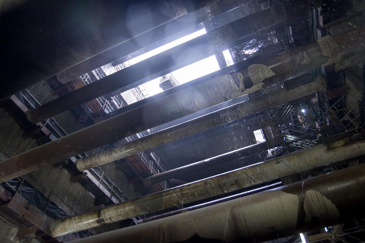 Interior view of underground transit station cavern with fluorescent lighting and concrete structural elements.